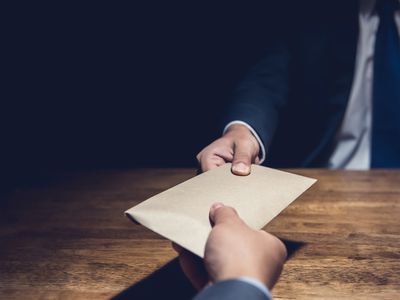 Cropped hands exchanging a brown envelope as bribery