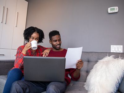 Young black couple looking at ways to lower their mortgage payment with laptop and paper