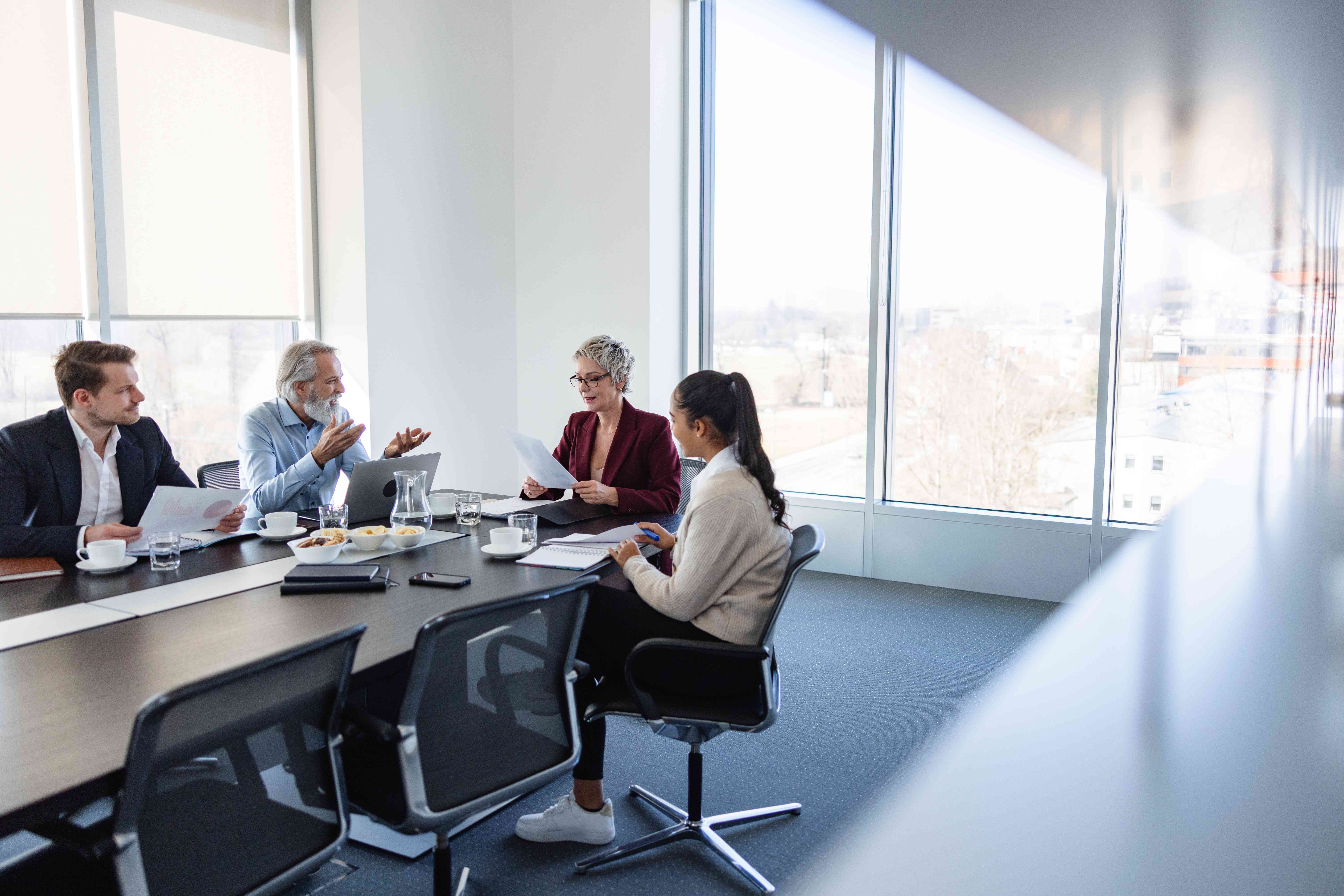 An unhappy shareholder sits at a conference table with their attorney and talks to a company representative as a secretary takes notes.