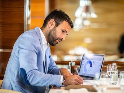 An entrepreneur writing on a document while sitting in a restaurant.