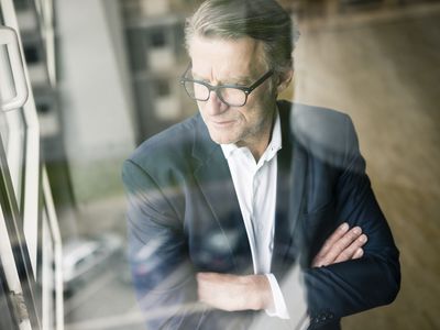 A businessman looking out the window with his arms crossed.