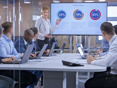 A businesswoman holding a presentation using display in glass conference room.