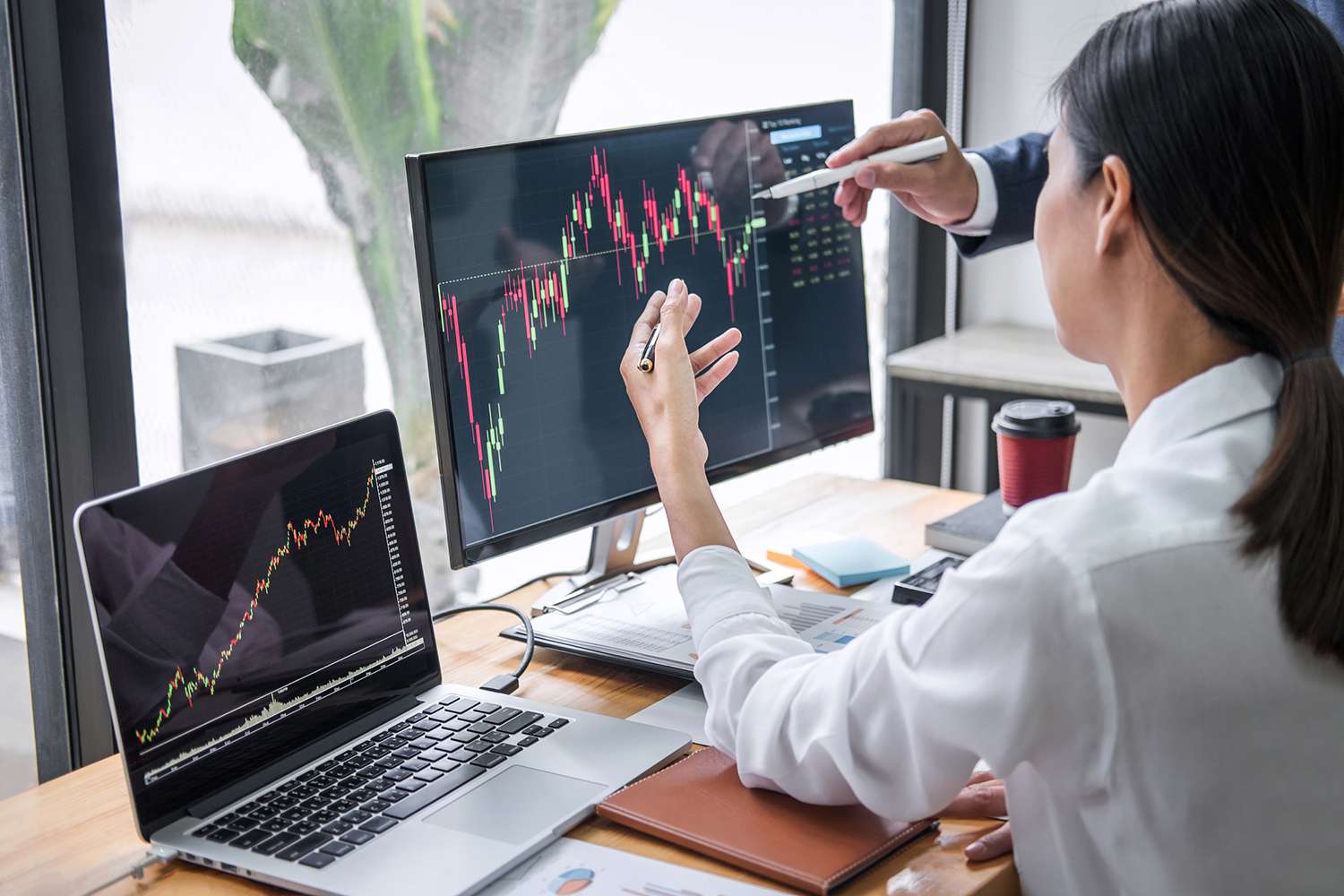 Businesswoman With Colleague Discussing Graph on Desktop