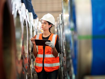 Sheet metal production worker checking stock in storage room in factory.