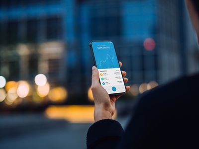 Over the shoulder view of a person using NFT investment wallet on smartphone in city street