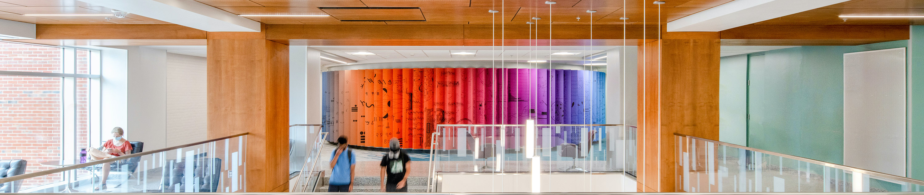 The exterior of the Cyma Rubin Visualization Gallery at Hill Library, a round room surrounded by hanging lights. Students descend the staircase just in front of the Studio.