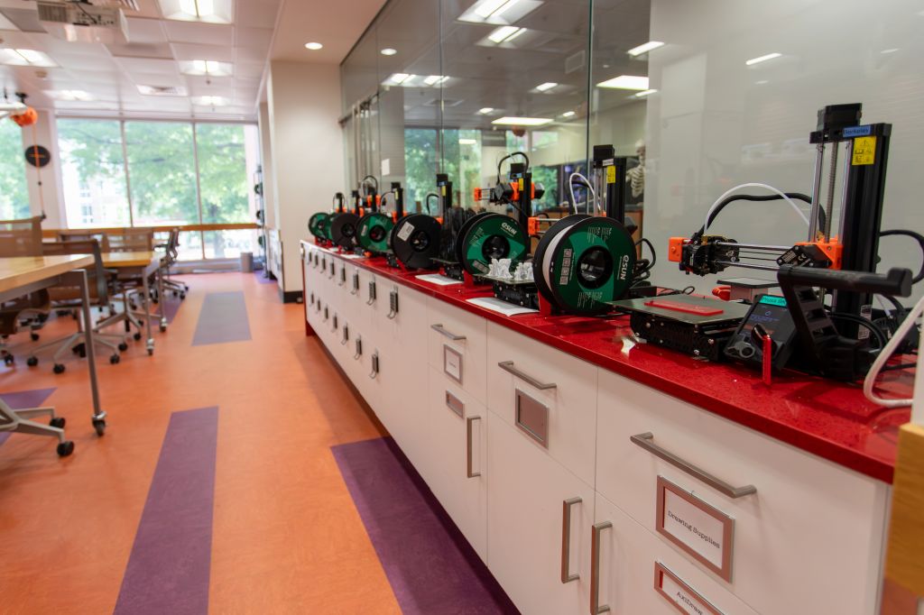 A row of 3D printers on a credenza