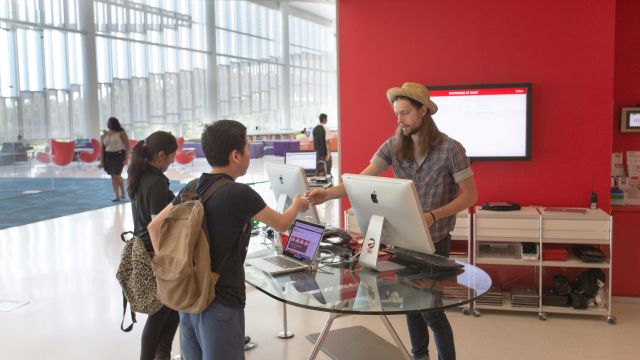 Library staff helping student at the Hunt Library Ask Us desk.