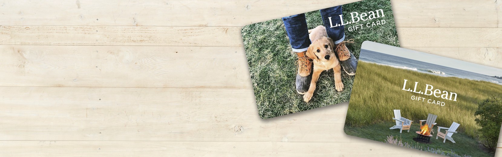 2 L.L.Bean gift cards on a light wood background.