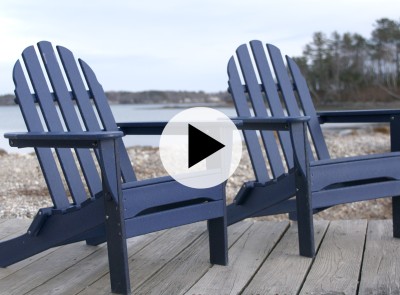 2 blue adirondack chairs on a deck overlooking the ocean.