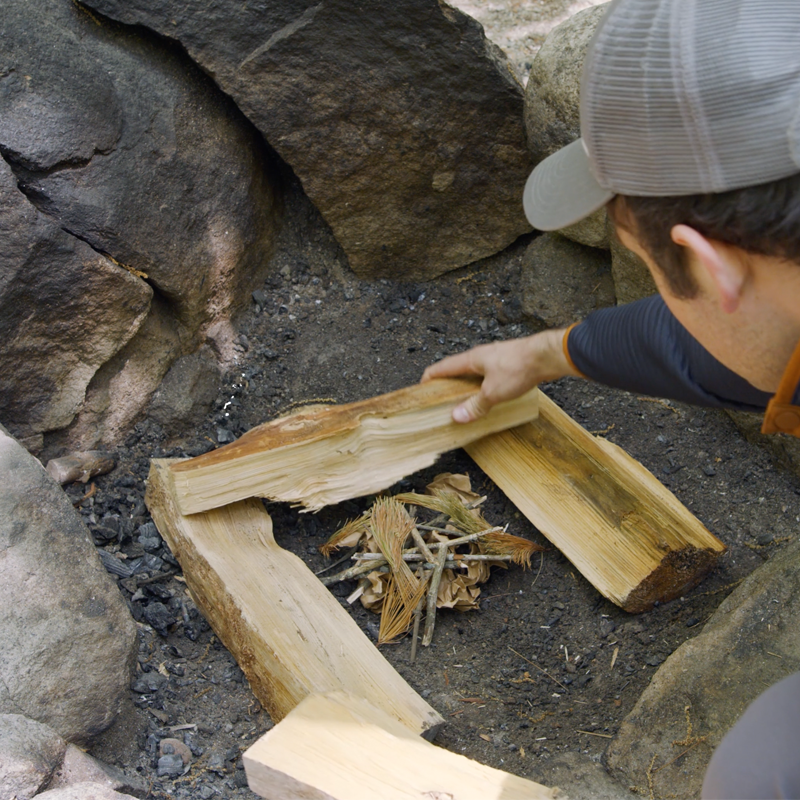 Nate stacking a second layer of fuel logs across the first two.