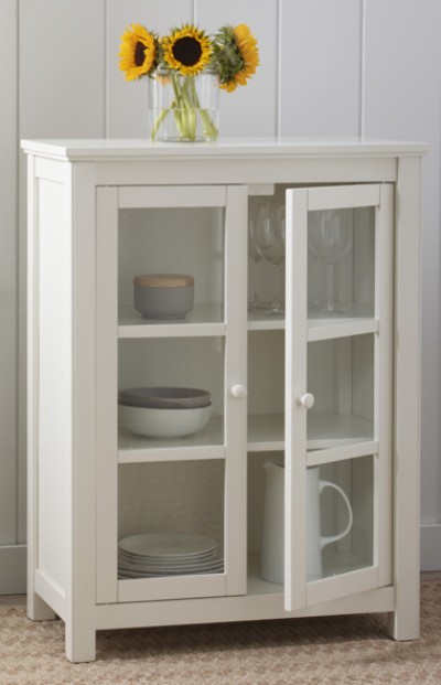 Image depicting a white cabinet with glass front and three shelves holding assorted dishes, and a floral vase on the top