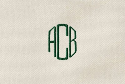 The letters "ACB" monogrammed in green thread on cream-colored canvas, the C larger than A and B, letters form a circle.