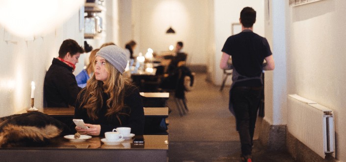 woman sitting in a cafe while using a smartphone