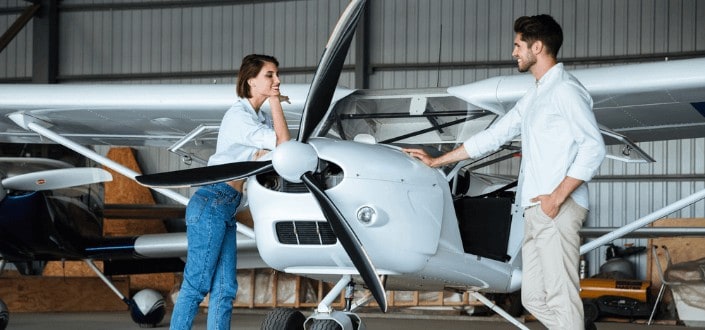 happy couple standing near an airplane