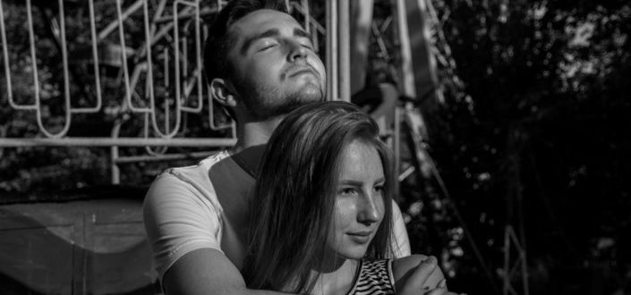 man hugging his girlfriend near a ferris wheel