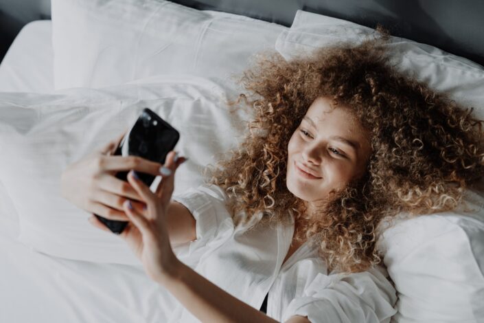 woman-in-white-button-up-shirt-lying-on-bed-