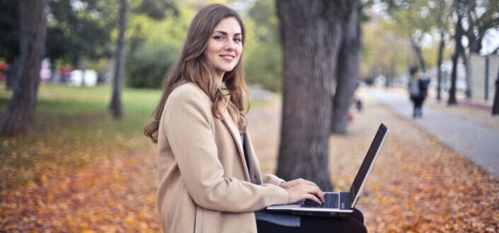 Joyful confident woman using netbook in park