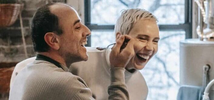 Laughing couple preparing food in kitchen