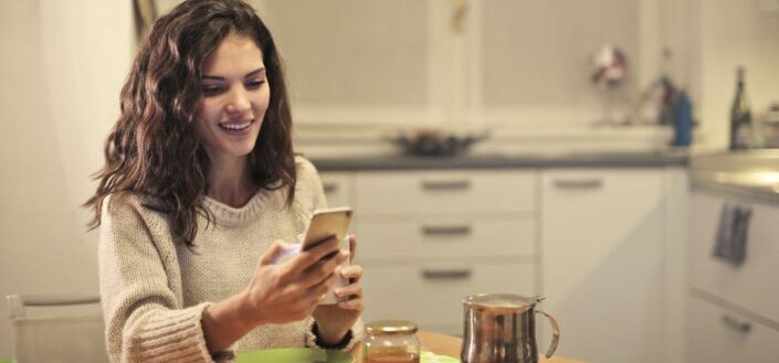 young-woman-drinking-tea-and-using-smartphone-