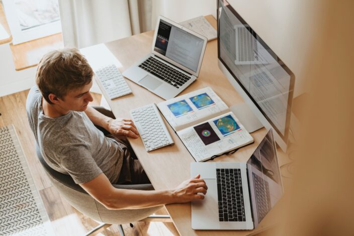 man-using-3-computers-