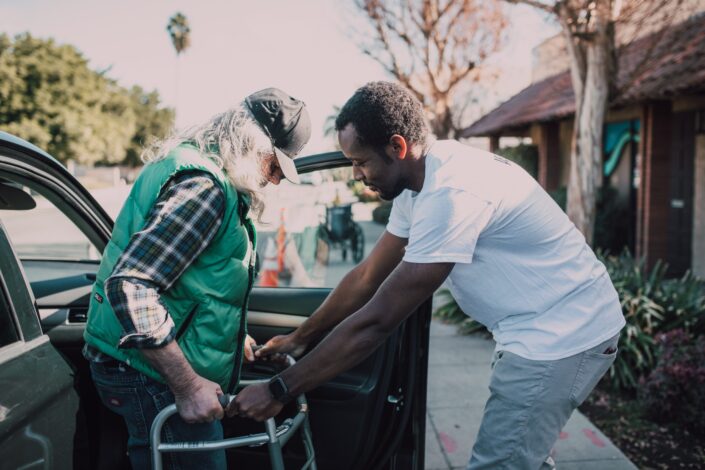 man-assisting-person-with-walker-