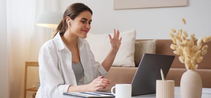 una mujer alegre que tiene una videollamada con alguien en una computadora portátil