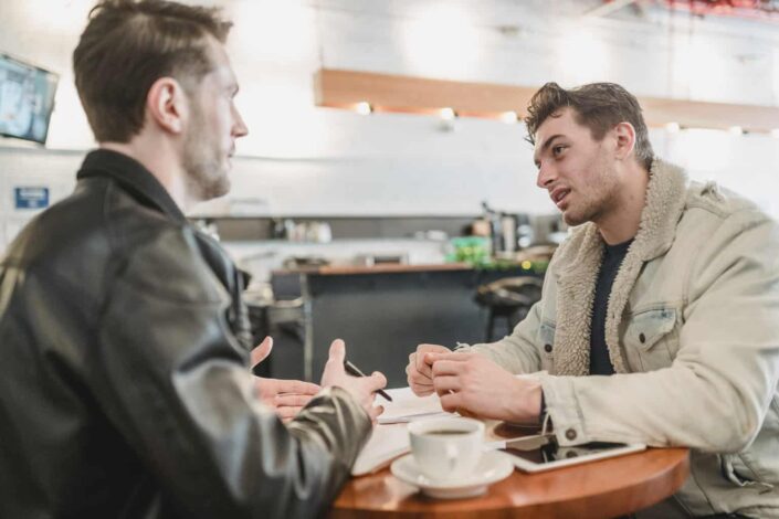 Compañeros de trabajo discutiendo el proyecto en la mesa con café