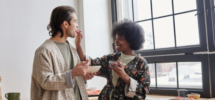 A woman feeding a man holding a bowl