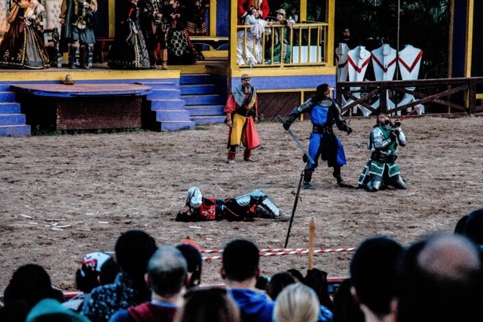 four men in renaissance outfits on a fair ground acting out a play