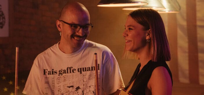 A man and a woman happily talking to each other while playing billiards