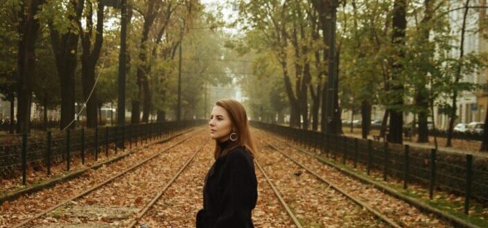 Woman in black coat standing on train rail