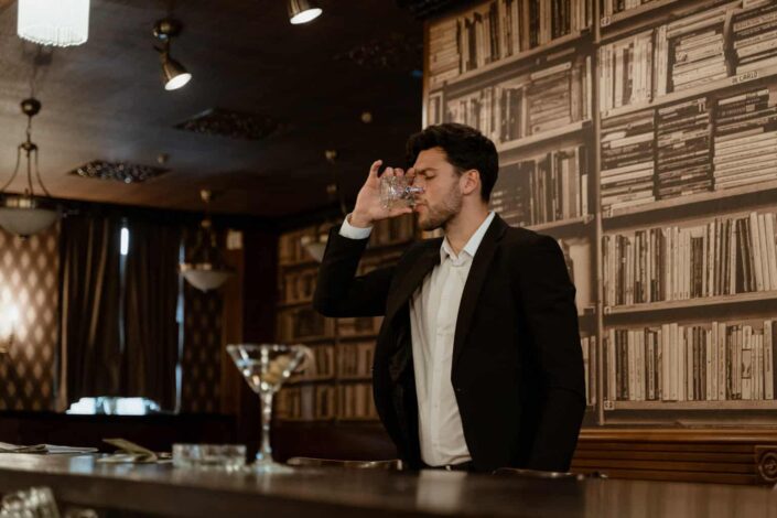 man in suit jacket drinking wine