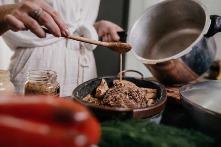 chef pouring sauce onto a meat dish