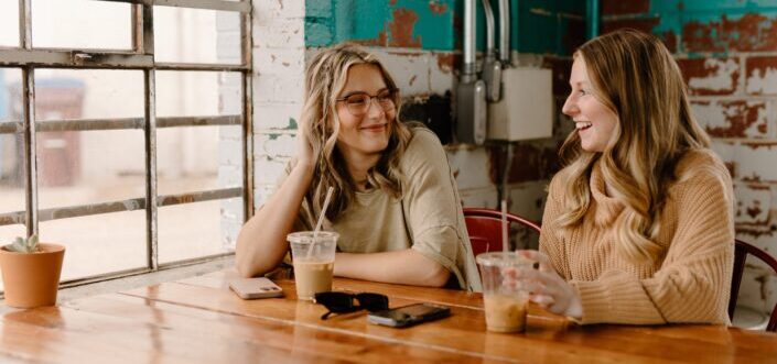 a couple of women sitting at a wooden table