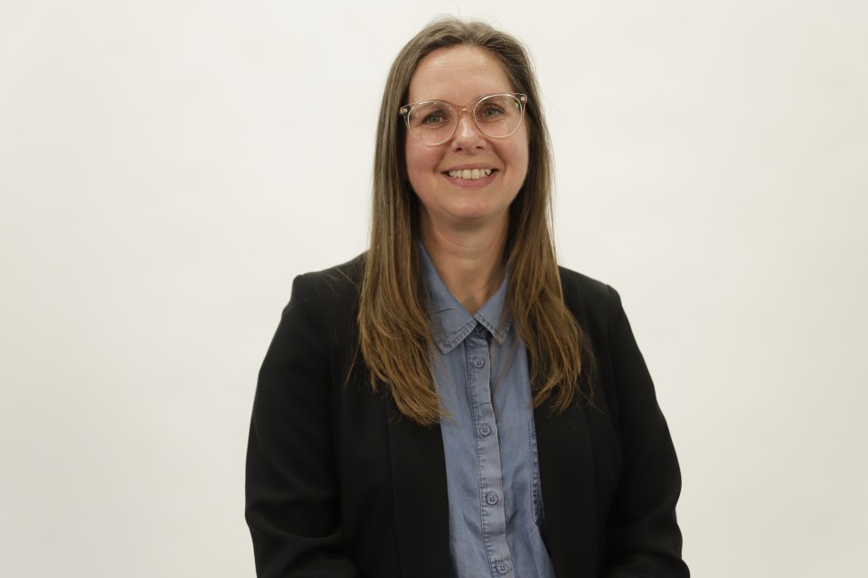 Rianne smiling wearing a blue button down blouse and a black blazer