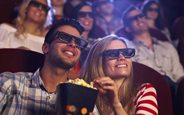 Gente viendo una película y comiendo palomitas de maíz.