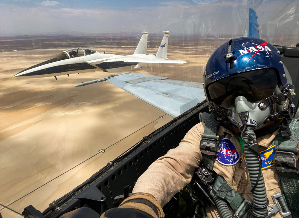 Selfie over the shoulder of a person flying in an airplane. Our the side window over the shoulder of the person is a second airplane in flight.