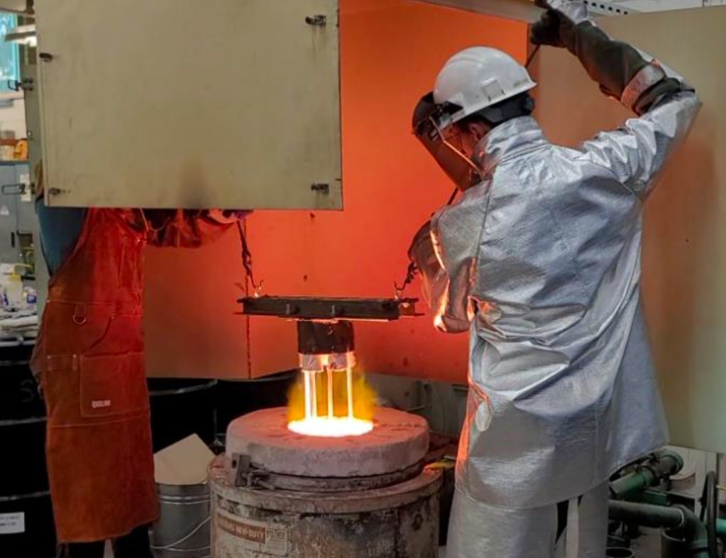 Colorado School of Mines team members are shown submerging the housing into a furnace holding simulated regolith melt > 1,300°C in the 2023 BIG Idea Challenge.