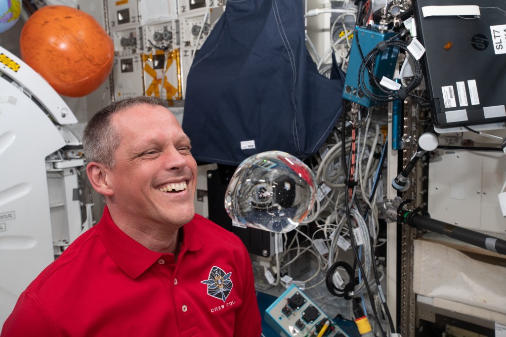 iss068e005874 (Oct. 1, 2022) --- NASA astronaut and Expedition 68 Flight Engineer Bob Hines has fun with fluid physics as he observes the behavior of a free-flying water bubble inside the International Space Station's Kibo laboratory module.