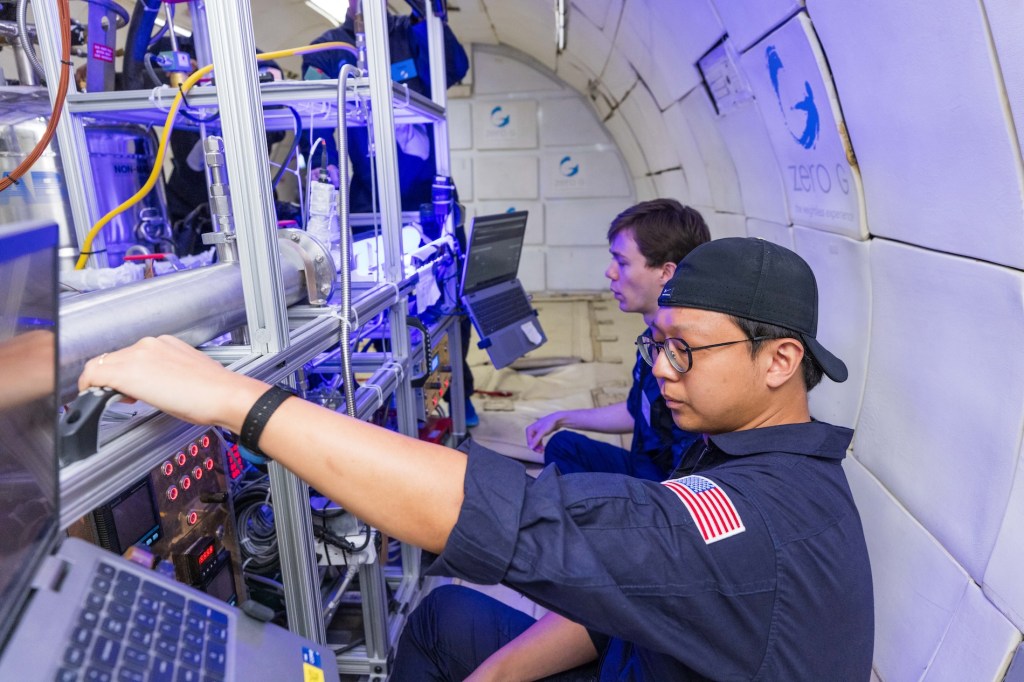 Two researchers study their experiment on a parabolic flight.