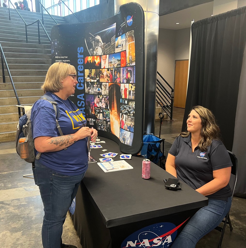 a woman visits the NASA Stennis table at Mississippi Comic Convention