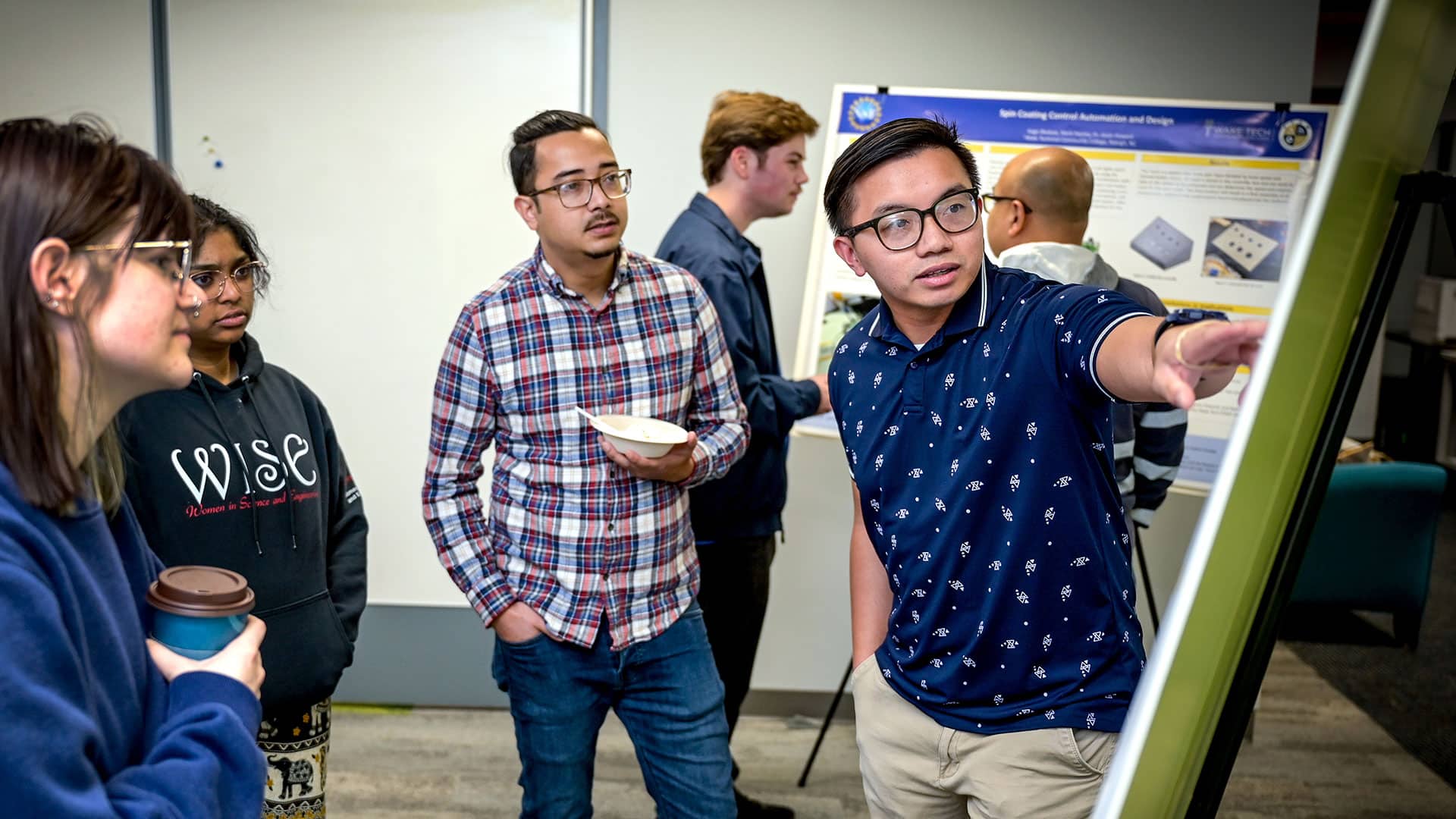 Community college students involved with Wake Technical Community College's SMART program gather around a poster.