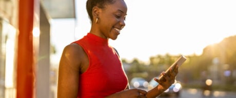 Young woman in red tank top using her smartphone to check her bank account.