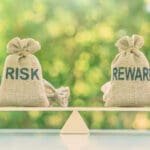 Risk reward ratio / risk management concept : Risk and reward bags on a basic balance scale in equal position, depicts investors use a risk reward ratio to compare the expected return of an investment