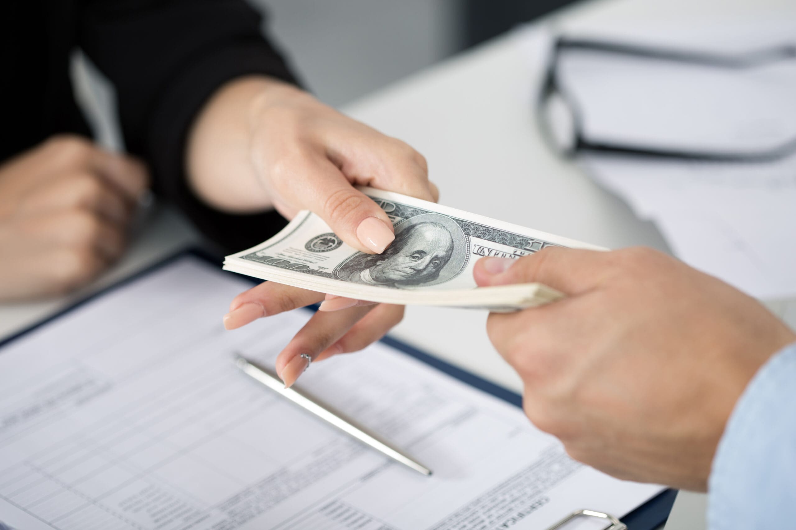 Woman taking batch of hundred dollar bills. Hands close up