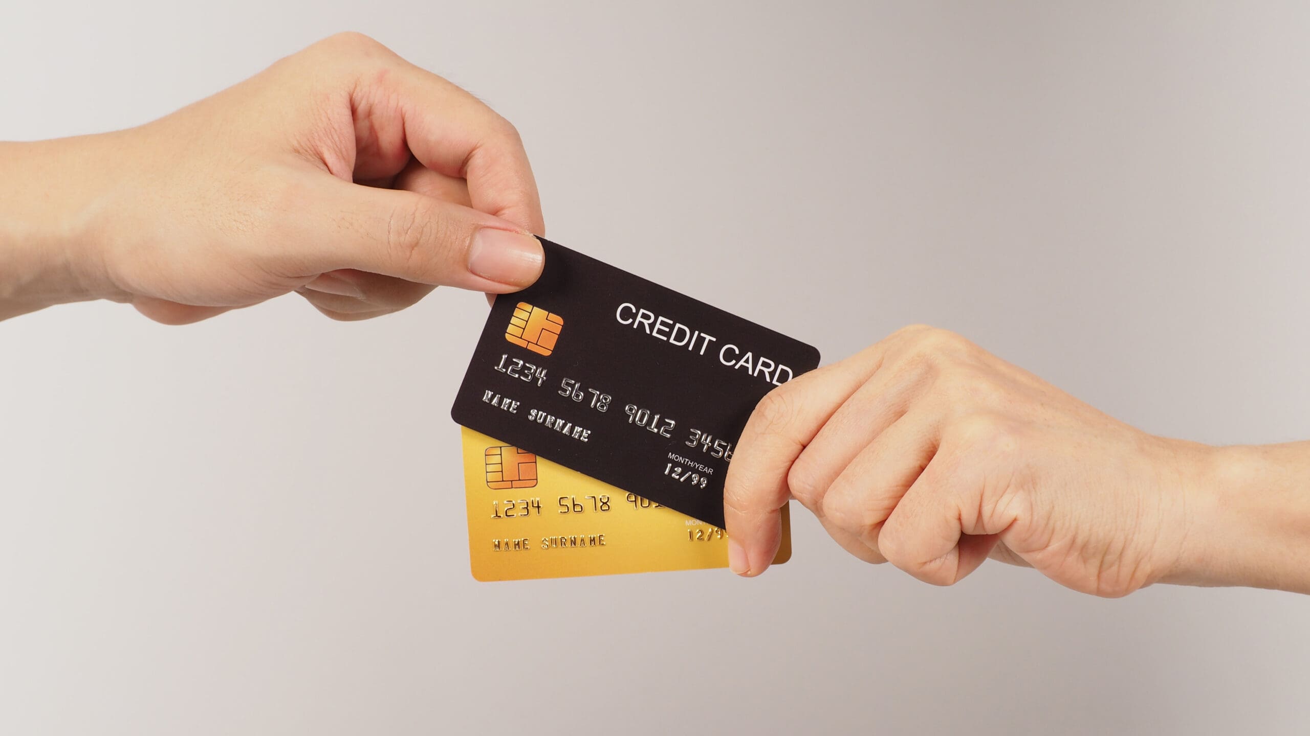 Hands are sent and receive black and gold credit cards on white background.