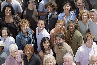 Crowd of smiling people looking up toward the camera.