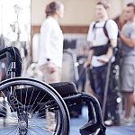 Man receiving physical therapy with wheelchair in foreground.