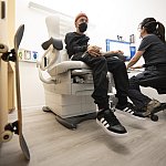 Man in hospital chair getting his vitals monitored by a technician.